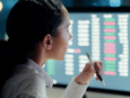 Business woman in white blouse holding a pen and thinking and working at computer