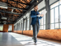 Businessman walking with laptop in empty office building.