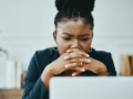 Shot of a young businesswoman frowning while using a laptop in a modern office