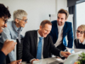 Joyful business people looking at laptop at the office and smiling