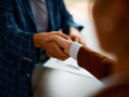 Two people shaking hands, one with a brown sleeve and one with a blue sleeve.