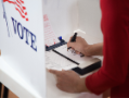 Voter in polling place checking a ballot