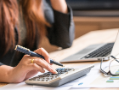 Close up of woman's hand pressed on calculator for counting monthly expense or planning money management.