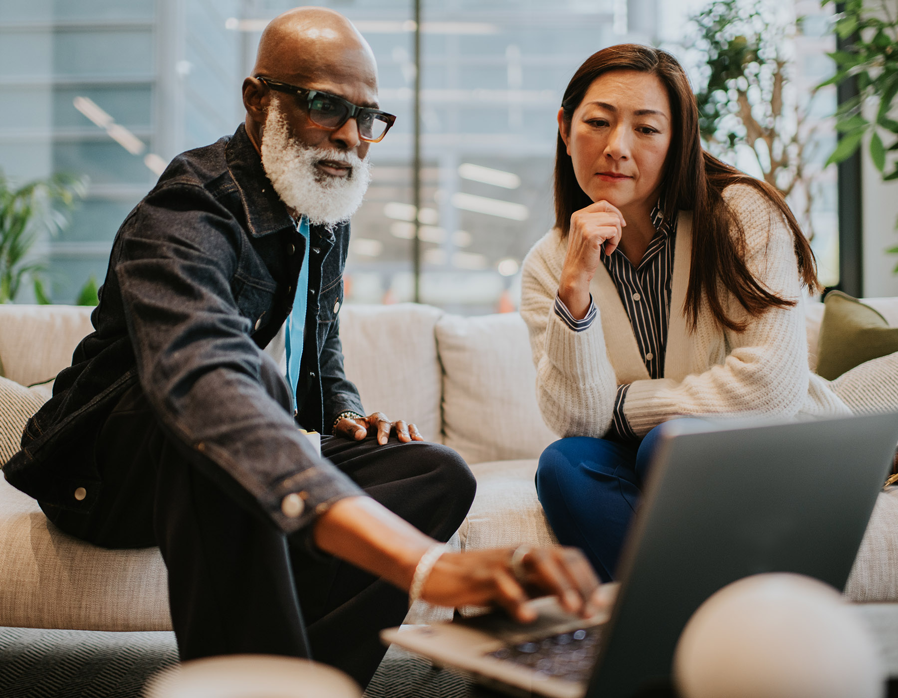 A man and a woman on a sofa in a office having a casual business meeting