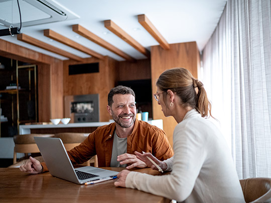 two people having a conversation while smiling over a laptop