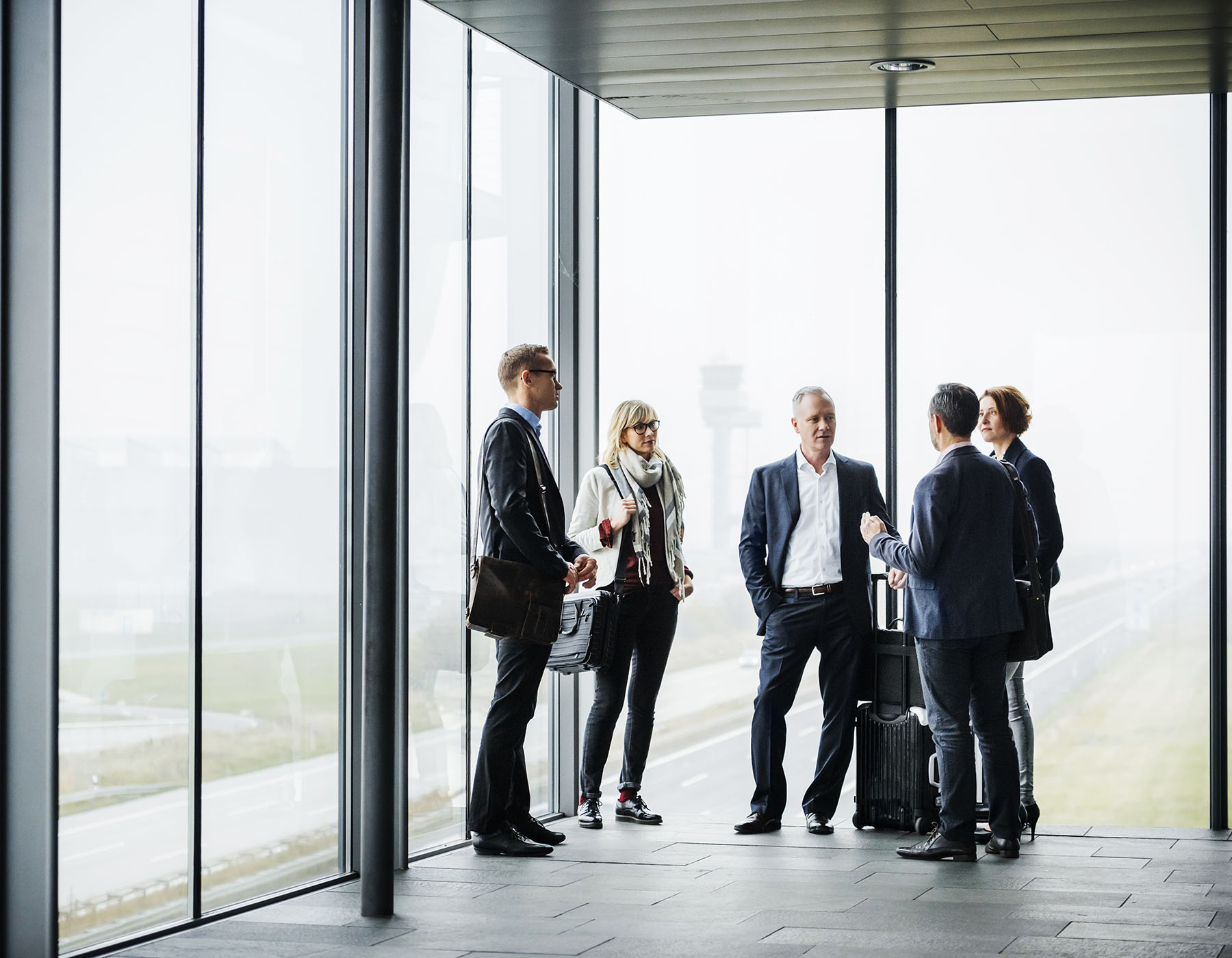 multi-generational group of business people standing and talking in an airport-like setting