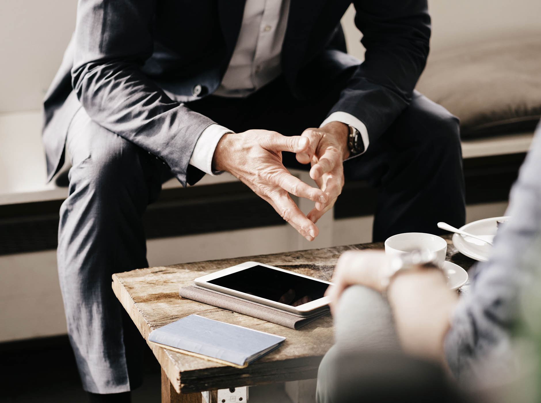 torso-view of suited business man, fingers touching, in meeting