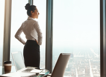 Caucasian business woman hands on hips standing look out window