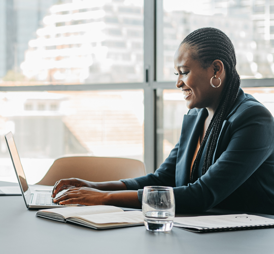 african american woman in suit at lap top in front of window in business office