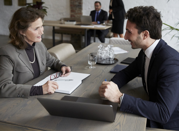 man and woman sitting at desk talking