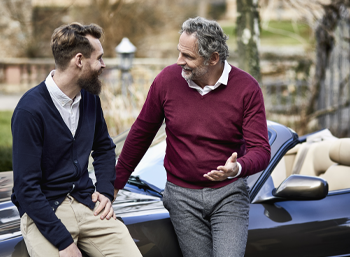 two intergenerational men, one old and one young, talking outside