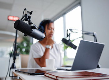 young diverse businesswoman with headphones and microphone in front of laptop