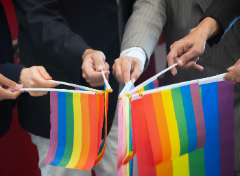 Multicultural team of professionals holding rainbow flags in solidarity.