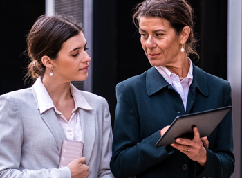 two caucasian women sitting in front of tablet