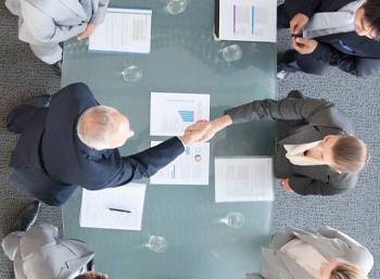 male, female business people around table with print outs in overhead stock image