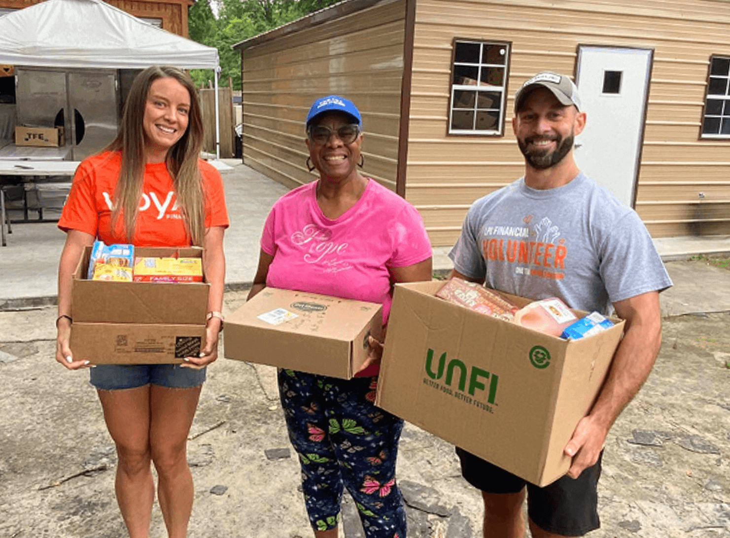 three people outside holding boxes as part of SMN community impact