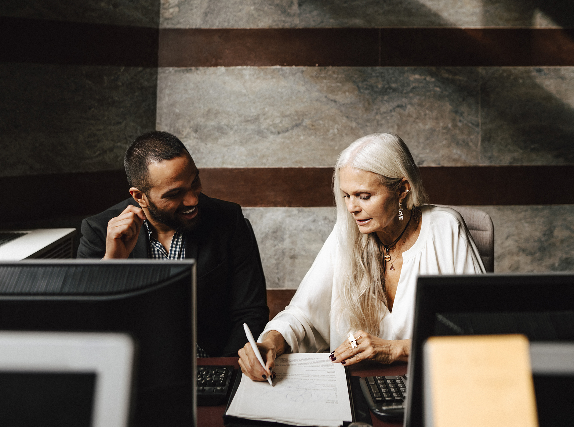 business woman and man reviewing text on sheet of paper in office