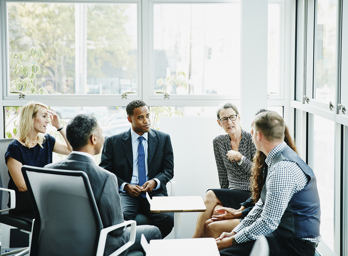 mature businesswoman leading small group seated in room with large window