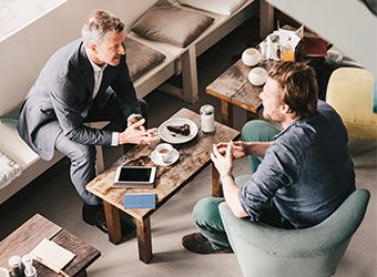 Two seated men talking in restaurant setting image